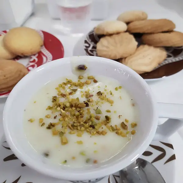 A cup of pistachio flavoured hot chocolate with biscuits